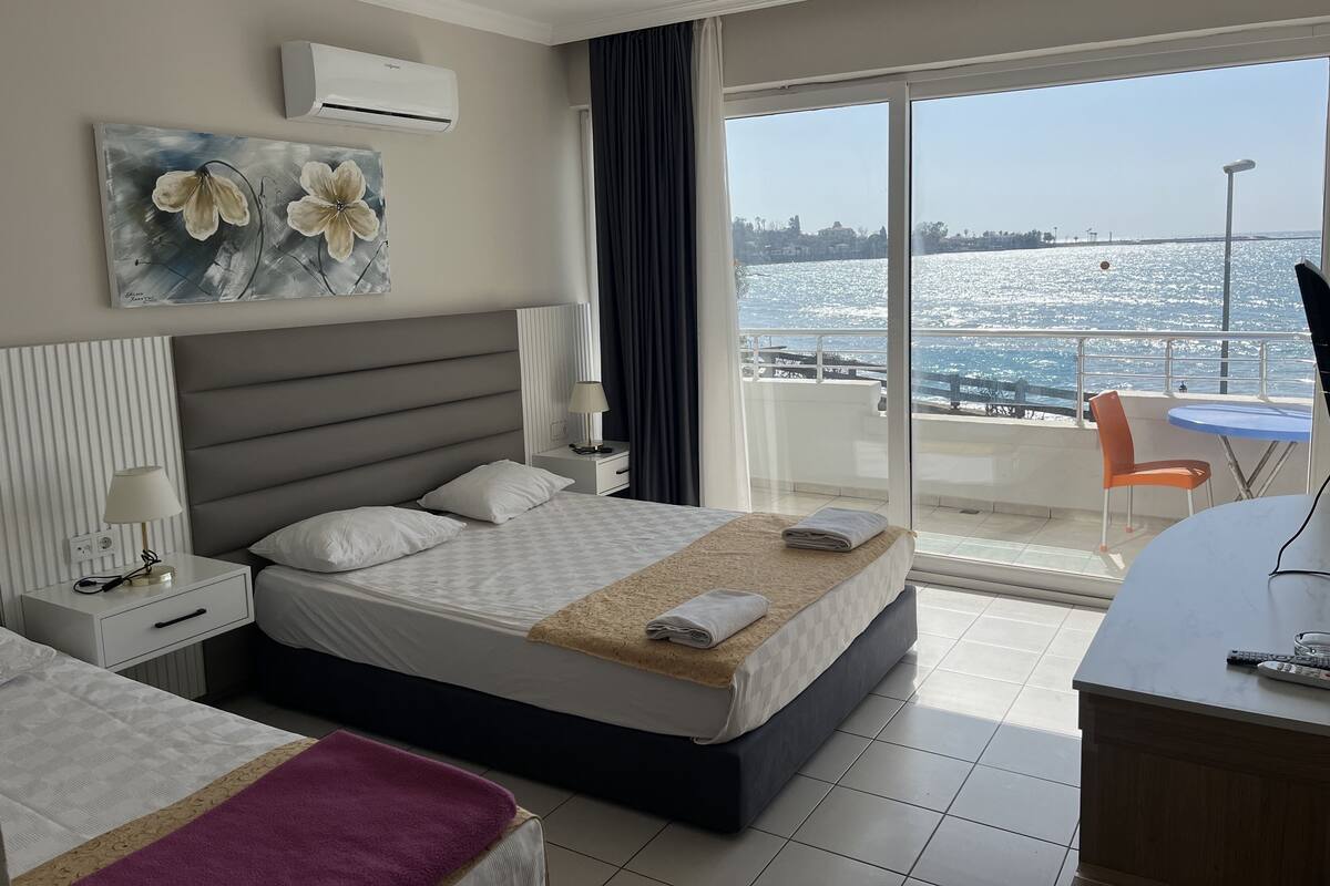 Una habitación de hotel con cama, mesita de noche, lámpara y vista al mar.
