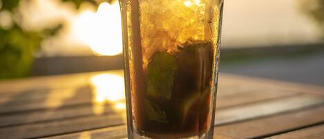 A tall glass with ice, a straw, and a lime slice on a wooden table.