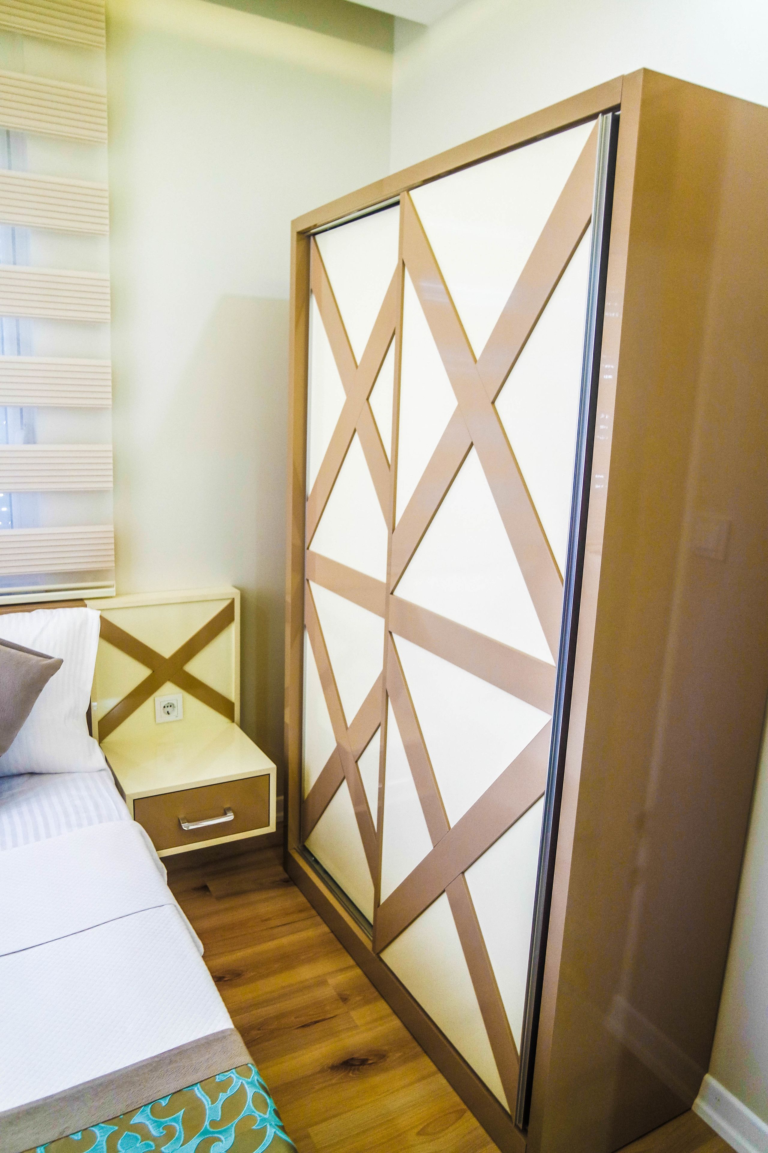 Ein Schlafzimmer mit Bett, Nachttisch, Holzschrank und einem Fenster mit Jalousien.