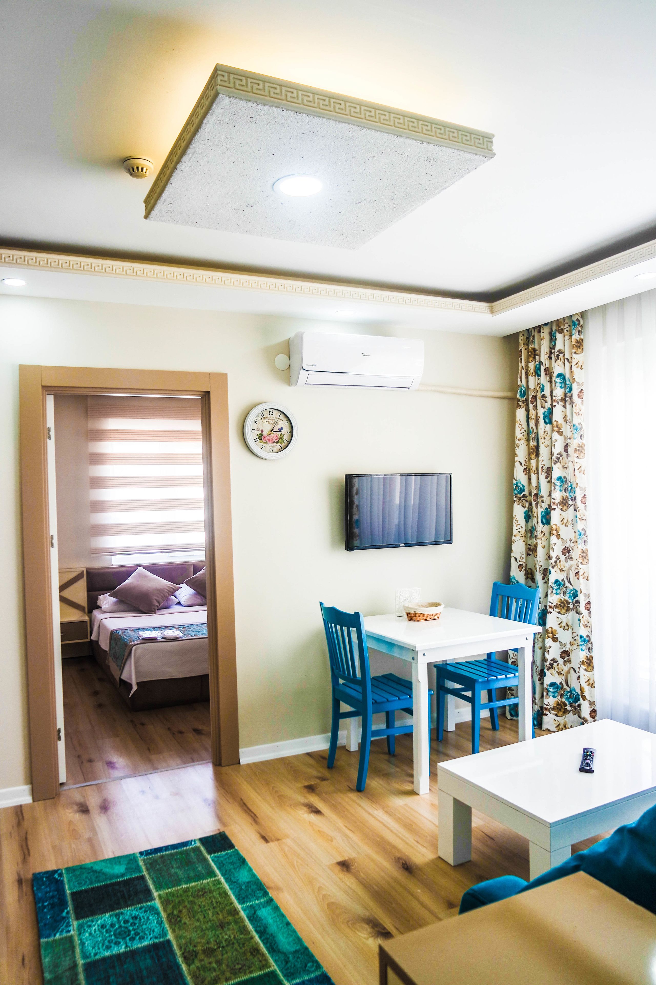 Quarto de hotel pequeno com cama, uma mesa, televisão e janela com cortinas.