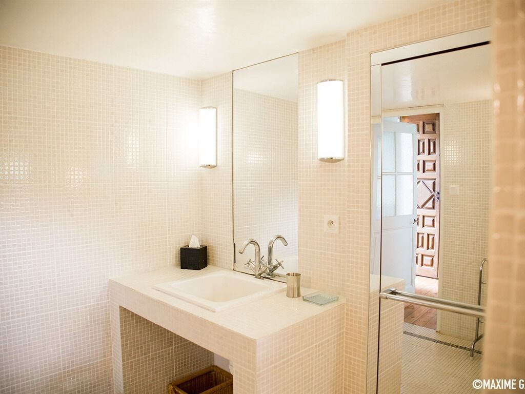 A modern bathroom with a large mirror, a sink, and a shower area.