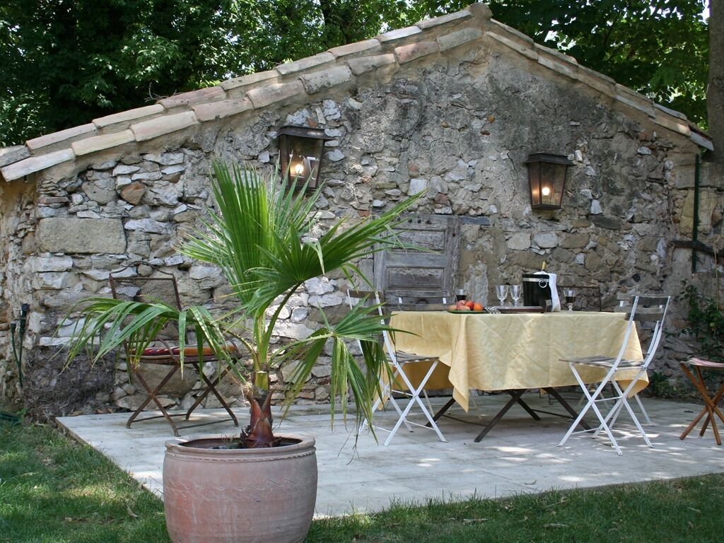 A stone building with a table and chairs set up outside.