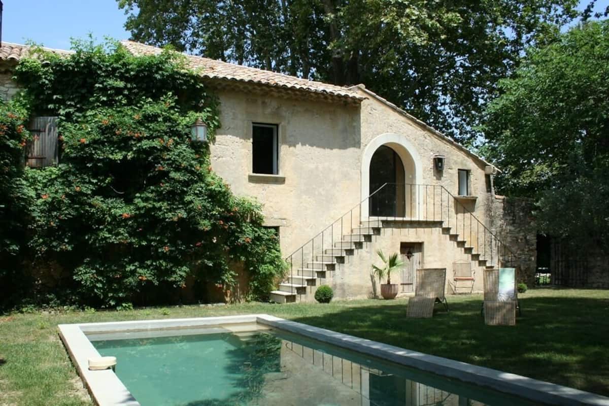 A rustic villa with a swimming pool, stone staircase, and lush greenery.