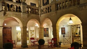 A courtyard with stone arches, red chairs, and potted plants. - Château Beaupré Deleuze (Saint-Laurent-des-Arbres)