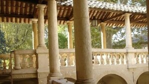 A covered outdoor area with stone columns and a tiled roof, featuring a stone balustrade and a staircase. - Château Beaupré Deleuze (Saint-Laurent-des-Arbres)