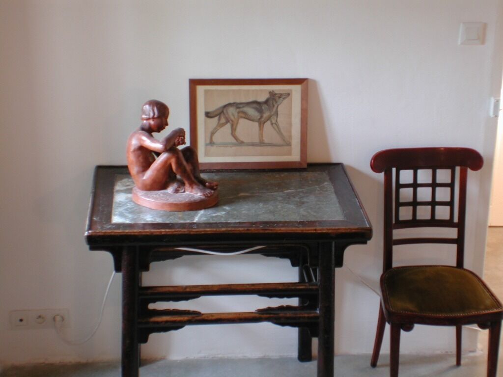 Una mesa de madera con una ilustración enmarcada de un animal y una escultura de una figura sentada.