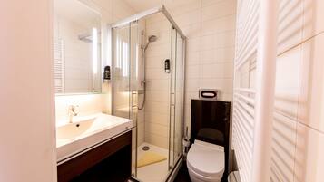 A modern bathroom with a glass-enclosed shower, a white sink, and a toilet.