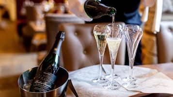 Una botella de vino siendo servida en tres copas de champán sobre una mesa con un mantel blanco.