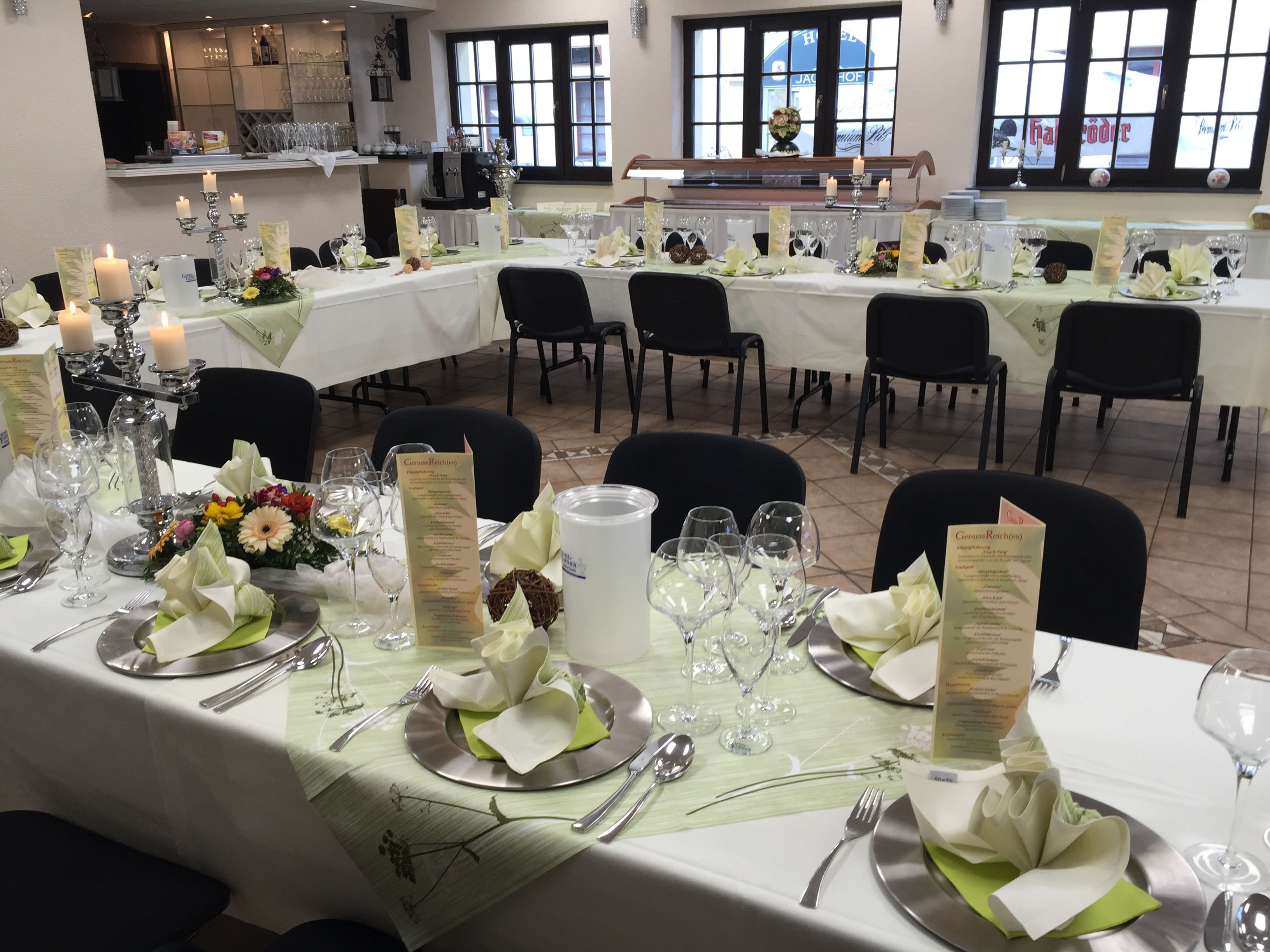 A restaurant with round tables set for dining, featuring menus, candles, and floral centerpieces.