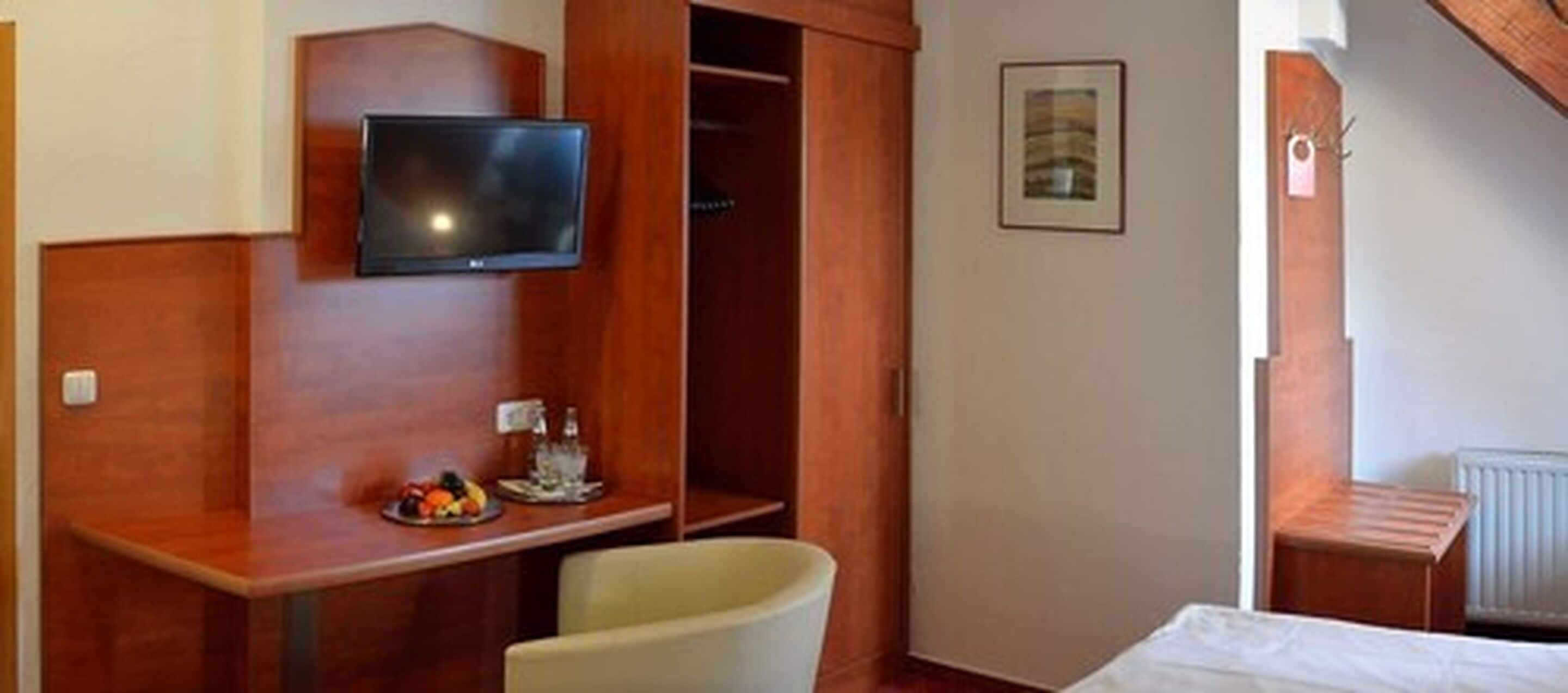 Ein Hotelzimmer mit einem Holztisch, einem Fernseher, einem Sessel und einem Bett.