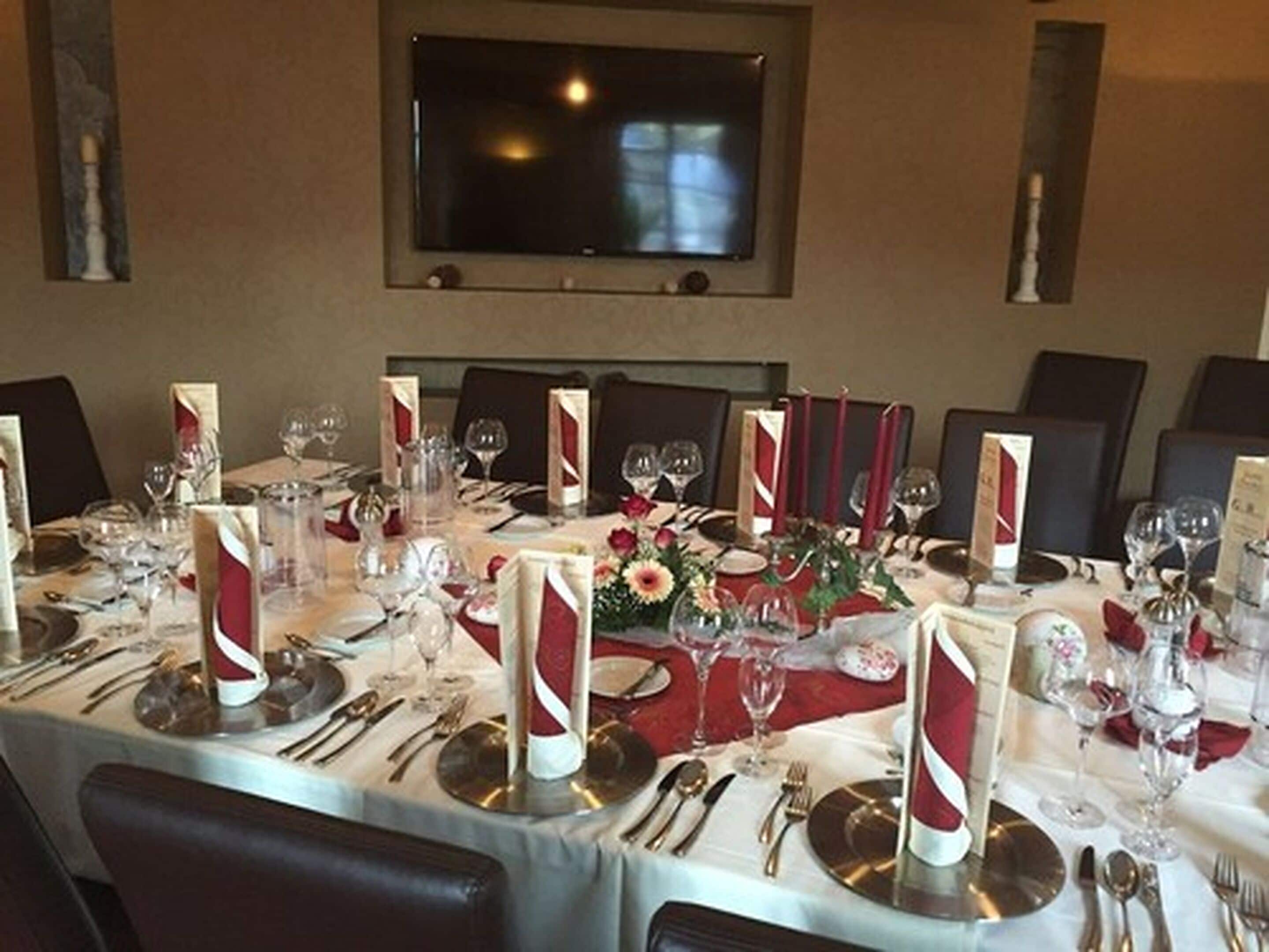 A formal dining table set with multiple place settings, glasses, and a centerpiece.