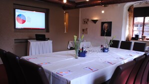 Une salle de conférence avec une longue table, des chaises, un écran de projection et un tableau au mur.