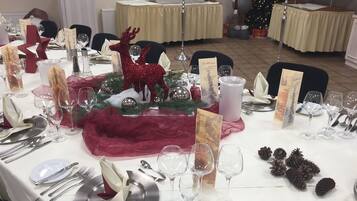 A festive table setting with a red reindeer centerpiece, candles, and a Christmas tree in the background.