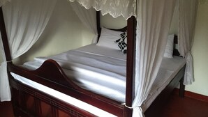A four-poster bed with white linens and a lace canopy.