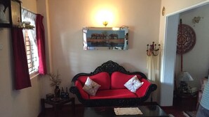 A living room with a red sofa, a black coffee table, and a painting on the wall.