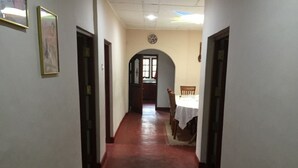A narrow hallway with a red floor leading to a dining area with a table and chairs.