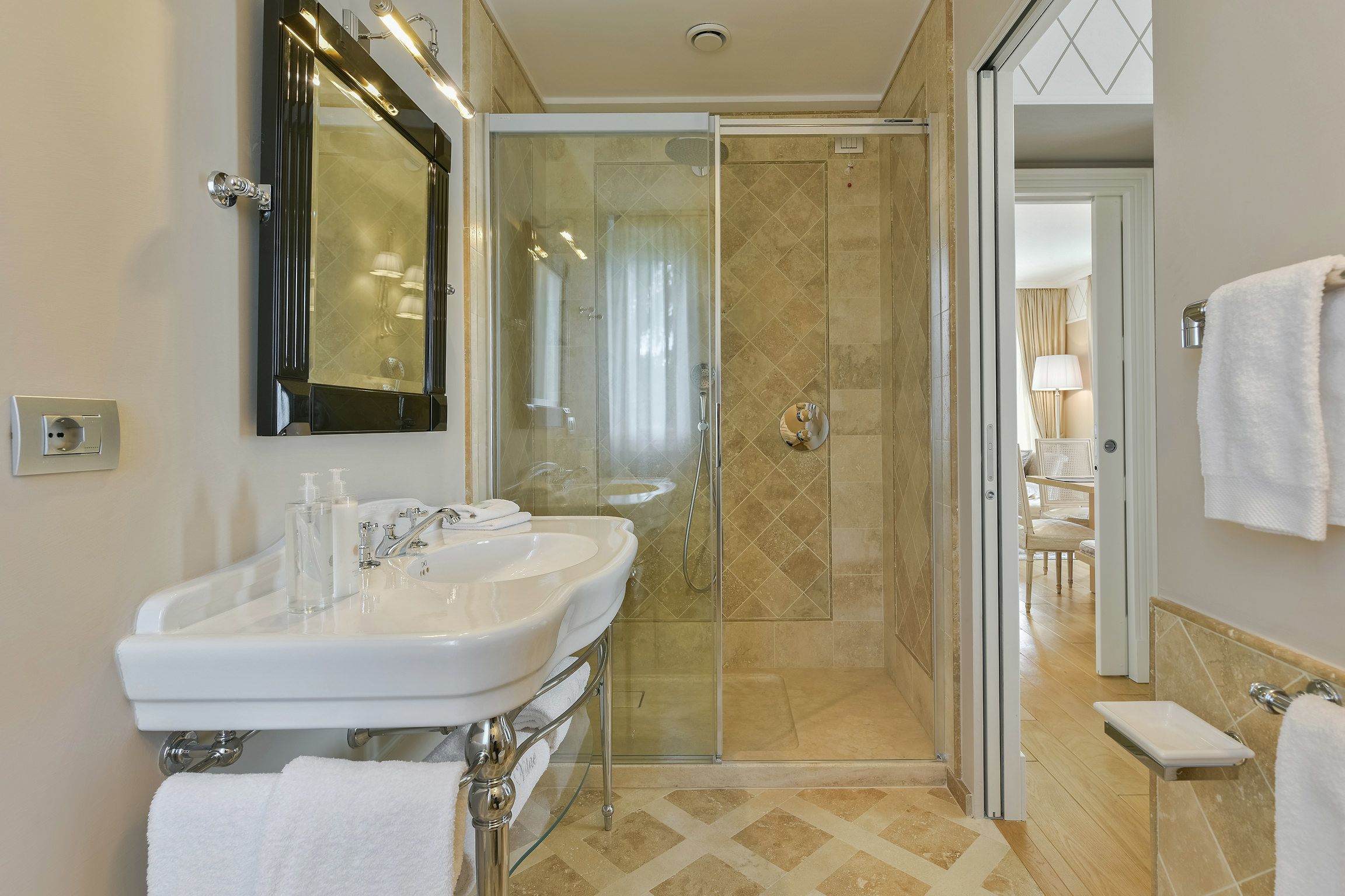 Un baño con ducha de vidrio, un lavamanos blanco y un espejo grande.