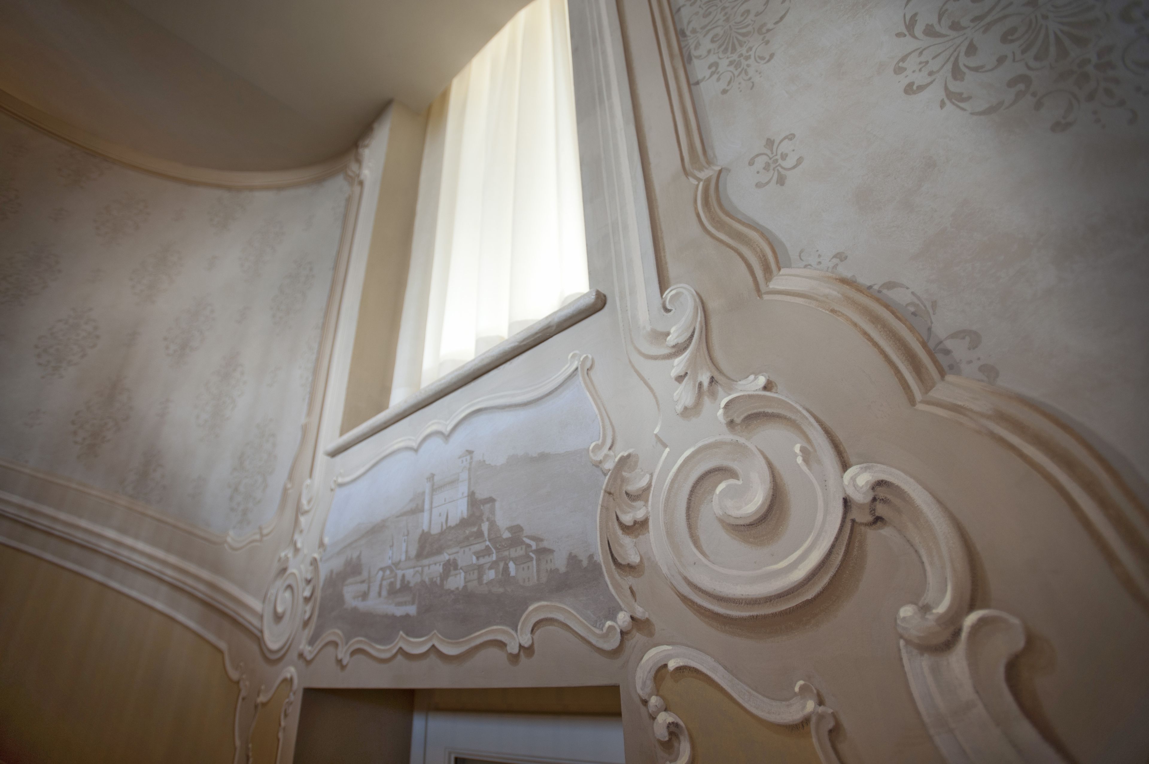 Een gedetailleerd architectonisch plafond met sierlijk houtsnijwerk en een raam.