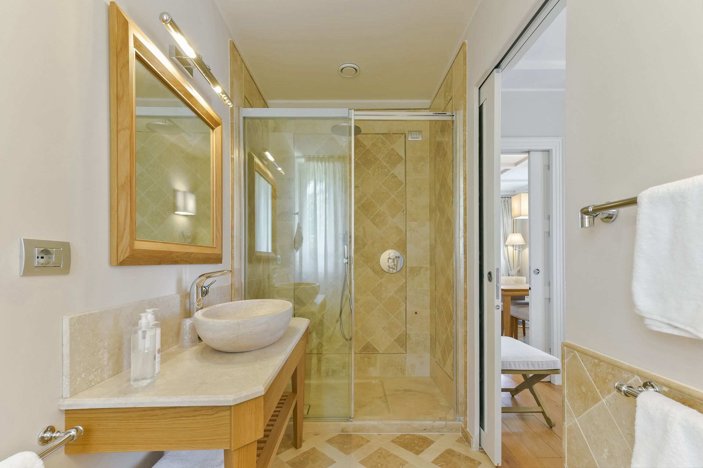 Un bany modern amb un lavabo gran, un plat de dutxa amb envàs de vidre i un moble de tocador de fusta.