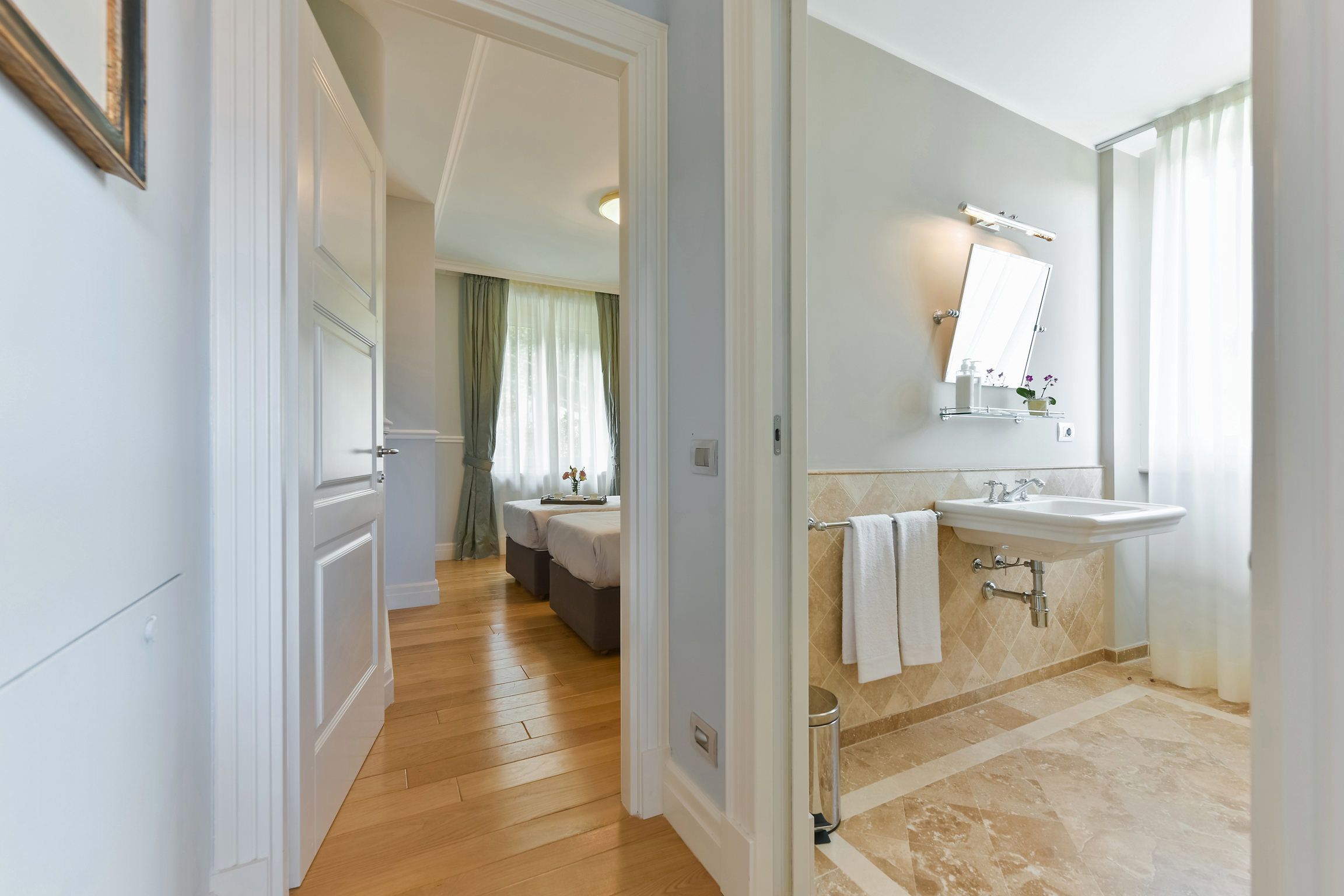 A hotel bathroom with a sink, mirror, and shower.