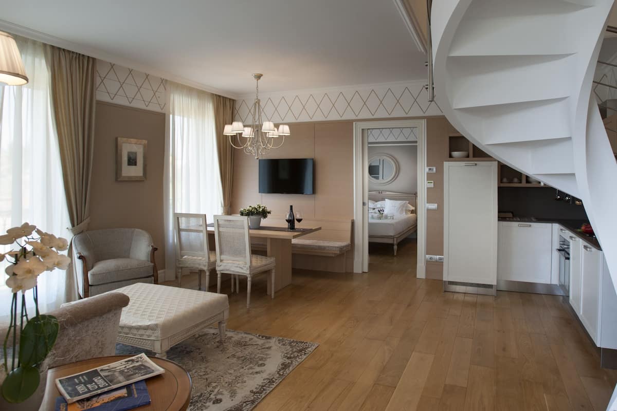 A modern living room with a dining area, a kitchen, and a spiral staircase.