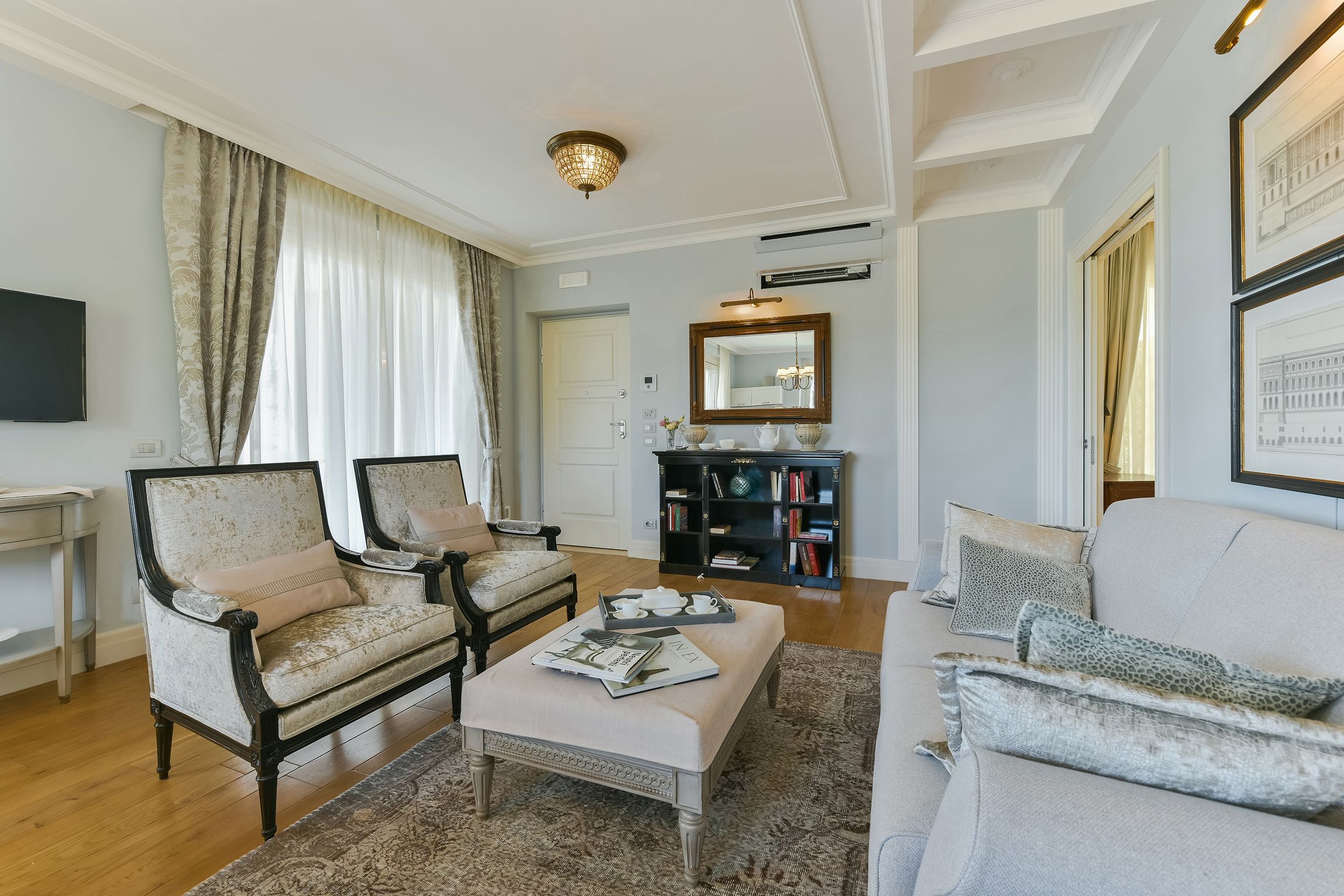 A living room with a sofa, two armchairs, a coffee table, and a bookshelf.