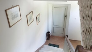 A staircase leading to a door with framed pictures on the wall. - La Coccinella Guest House (Pisa)