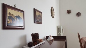 A dining area with a long table, framed pictures on the wall, and a small decorative item on the table. - La Coccinella Guest House (Pisa)