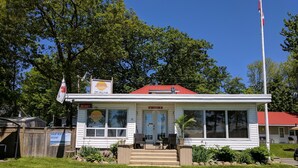 A small, single-story building with a red roof, a Canadian flag, and a sign indicating it is a vacation rental. - Balm Beach Resort & Motel (Tiny)