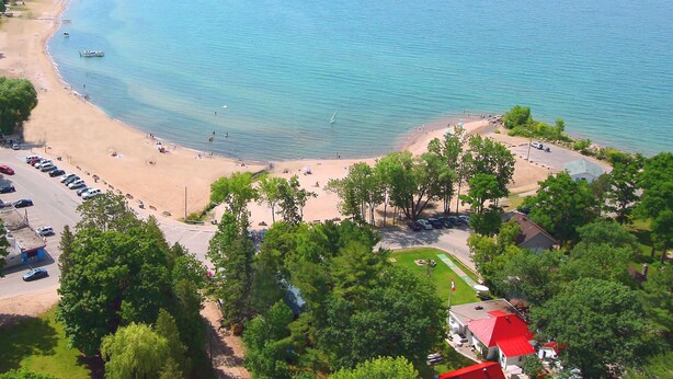 A coastal beach with a parking area and a building with a red roof. - Balm Beach Resort & Motel (Tiny)