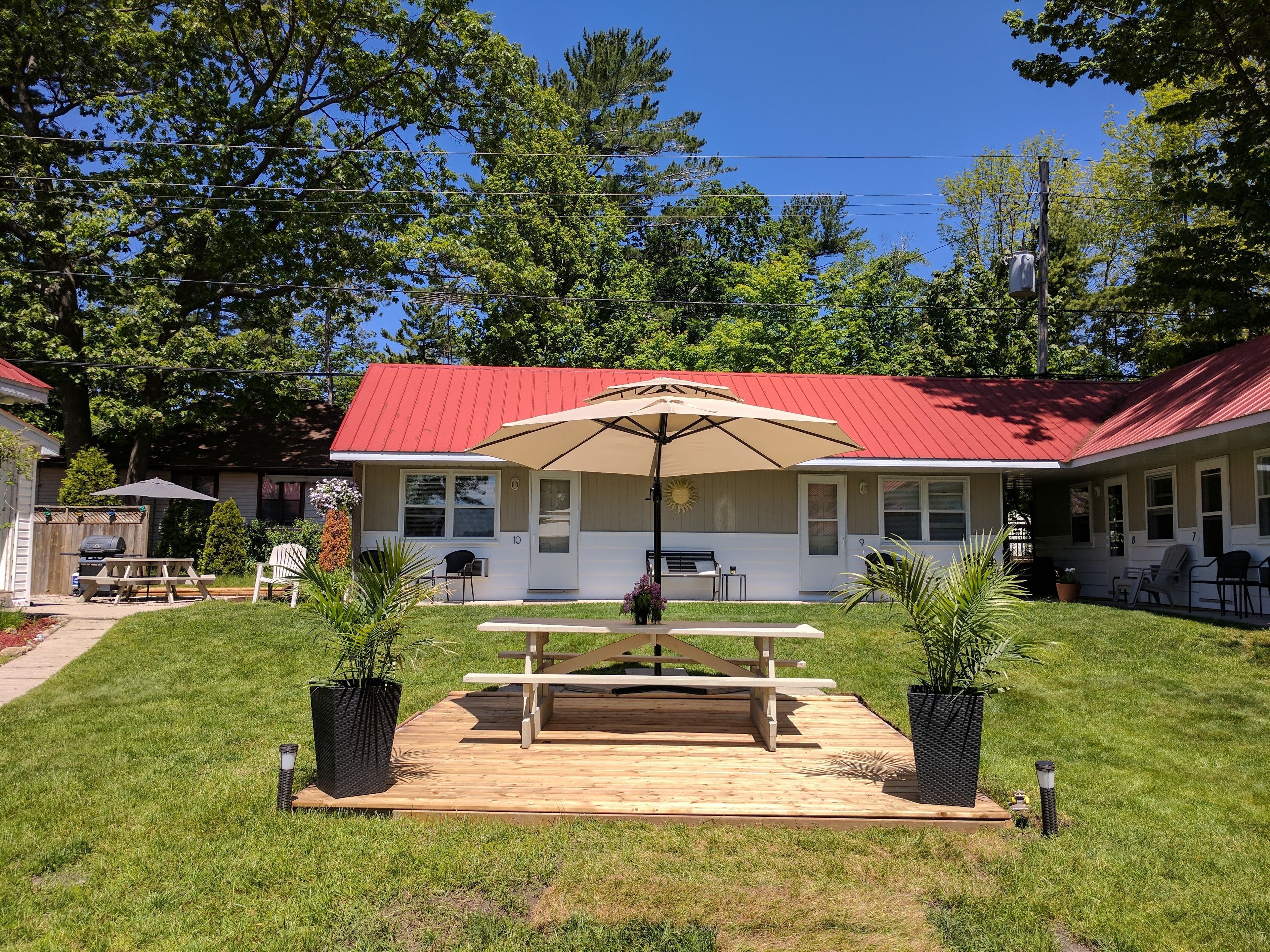 A house with a red roof, a patio with a table and chairs, and a large umbrella.
