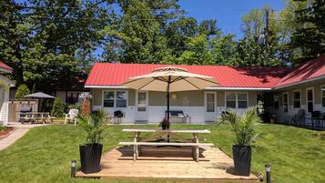 A house with a red roof, a patio with a table and chairs, and a large umbrella.