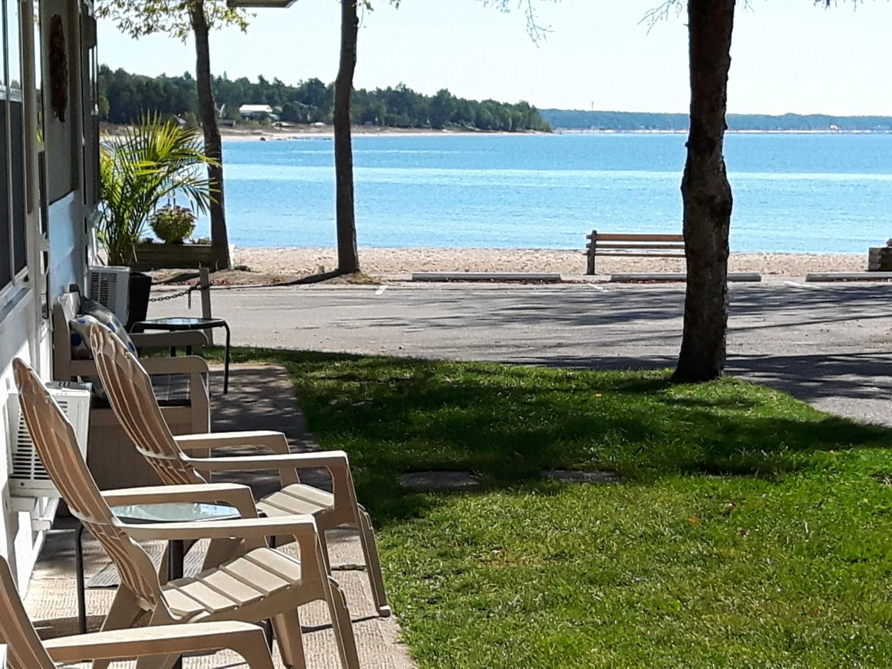A patio with outdoor seating, a view of the sea, and a grassy area.