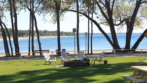 A picnic area with benches and a picnic table by a body of water, surrounded by trees. - Balm Beach Resort & Motel (Tiny)