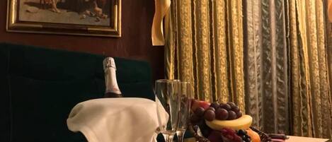 Een tafel met een champagnefles, een glas en een fruitschaal.