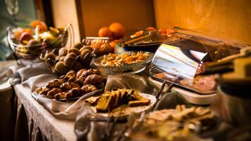 Una mesa de buffet con diferentes alimentos, como frutas, pasteles y una vitrina.