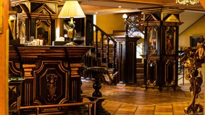 A grand hall with ornate wooden furniture, a staircase, and a chandelier. - Hotel Ambassador (Timisoara)