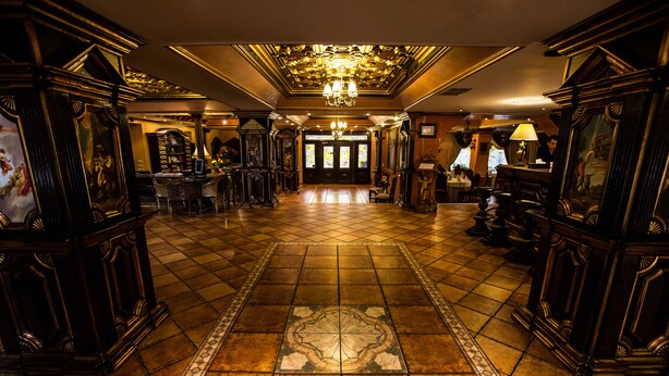A grand lobby with a tiled floor, ornate furniture, and a chandelier. - Hotel Ambassador (Timisoara)