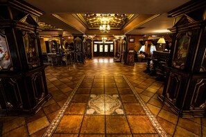 A grand lobby with a tiled floor, ornate furniture, and a chandelier. - Hotel Ambassador (Timisoara)