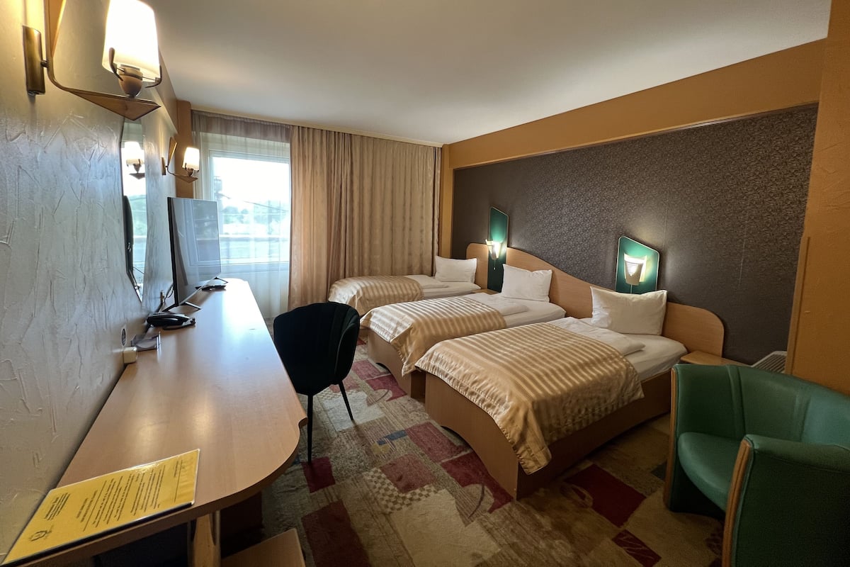 Ett hotellrum med två sängar, ett skrivbord, en stol och ett litet bord.