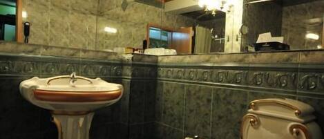 A bathroom with a pedestal sink, two toilets, and a mirror.