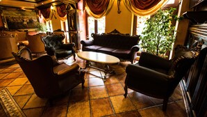 A room with a large round table surrounded by four armchairs, a sofa, and a potted plant. - Hotel Ambassador (Timisoara)