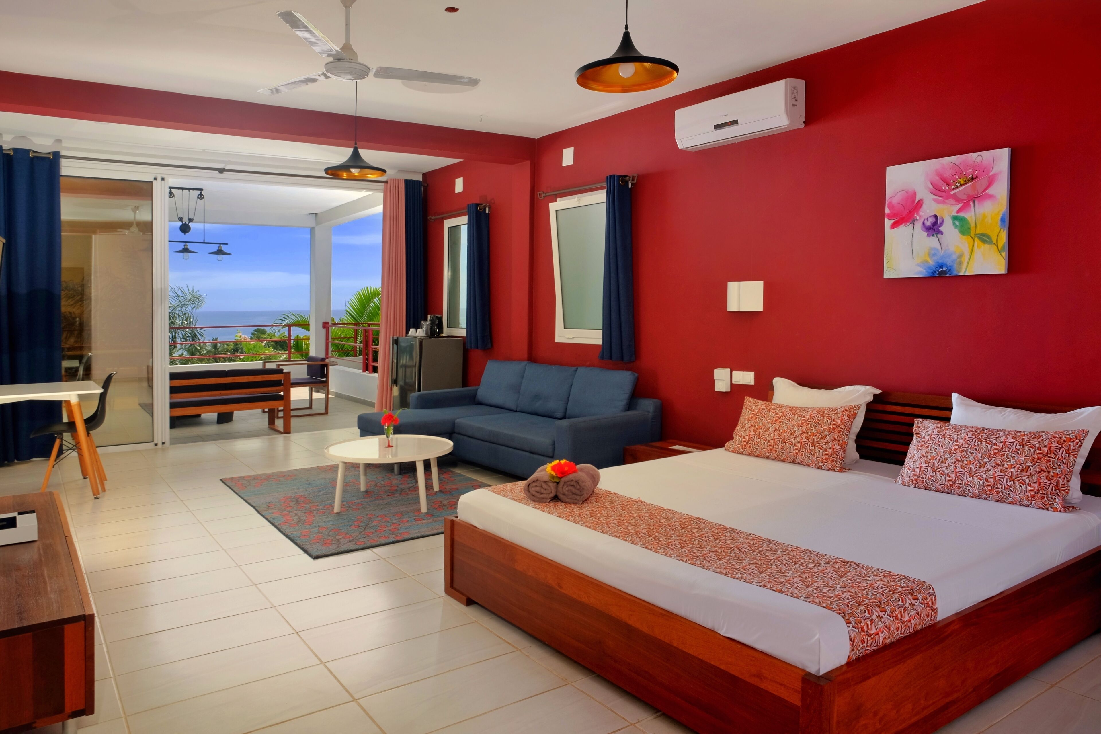 A hotel room with a large bed, a sofa, a desk, and a view of the ocean.