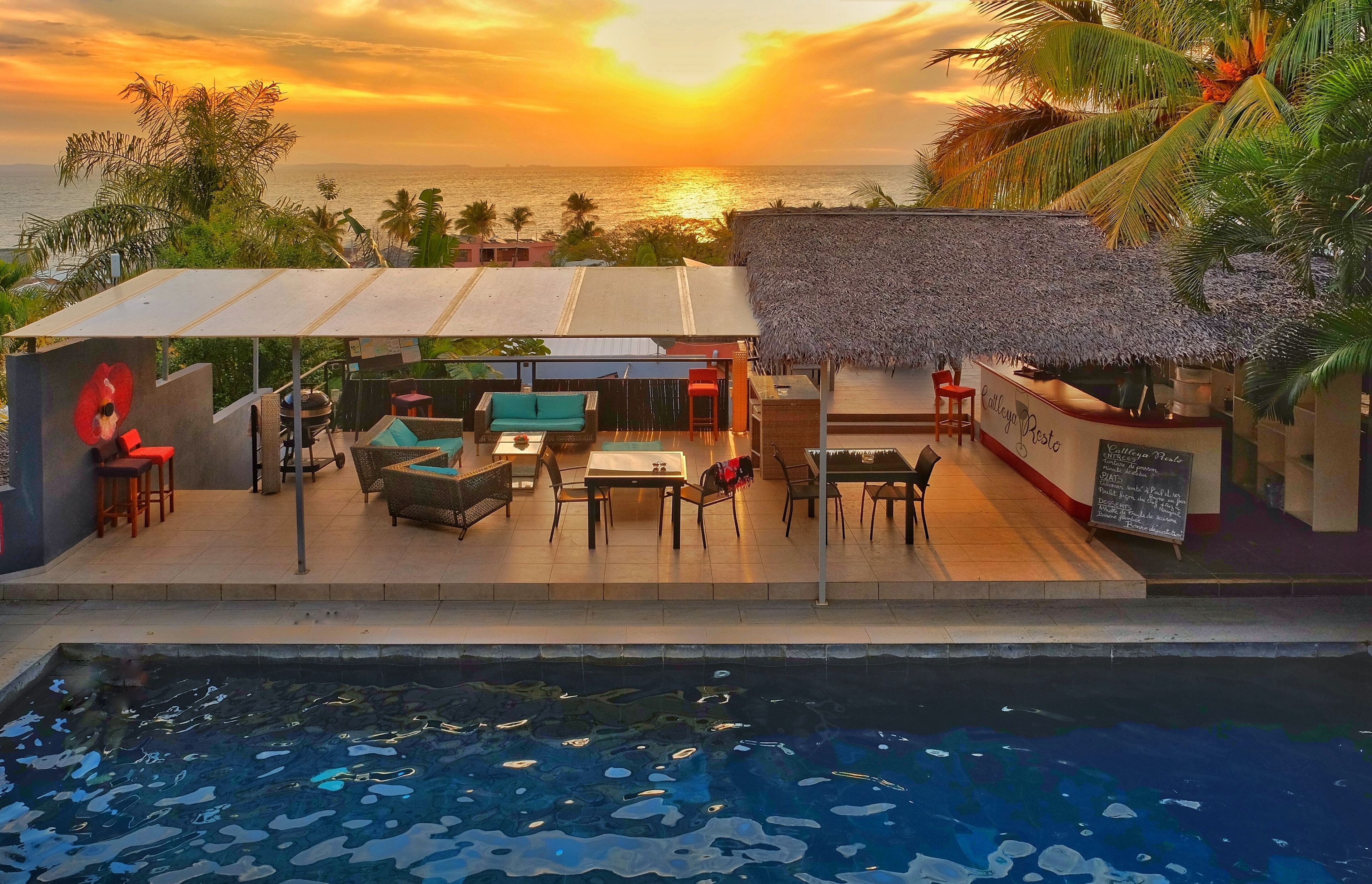 A poolside area with a thatched-roof bar and outdoor seating.
