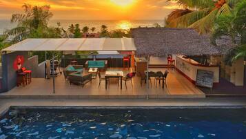 A poolside area with a thatched-roof bar and outdoor seating.