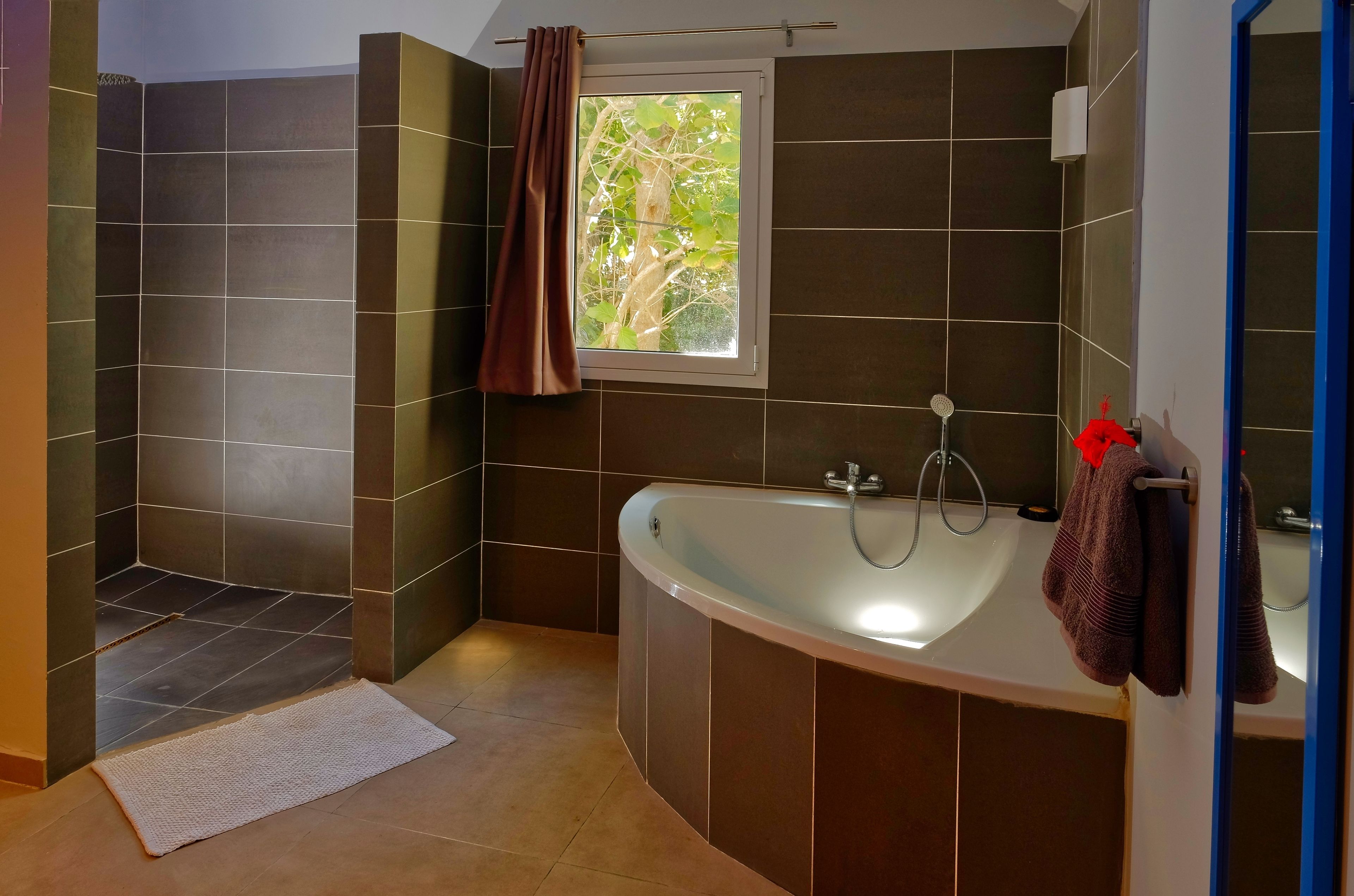 A modern bathroom with a bathtub, a shower area, and a window with a view of trees.