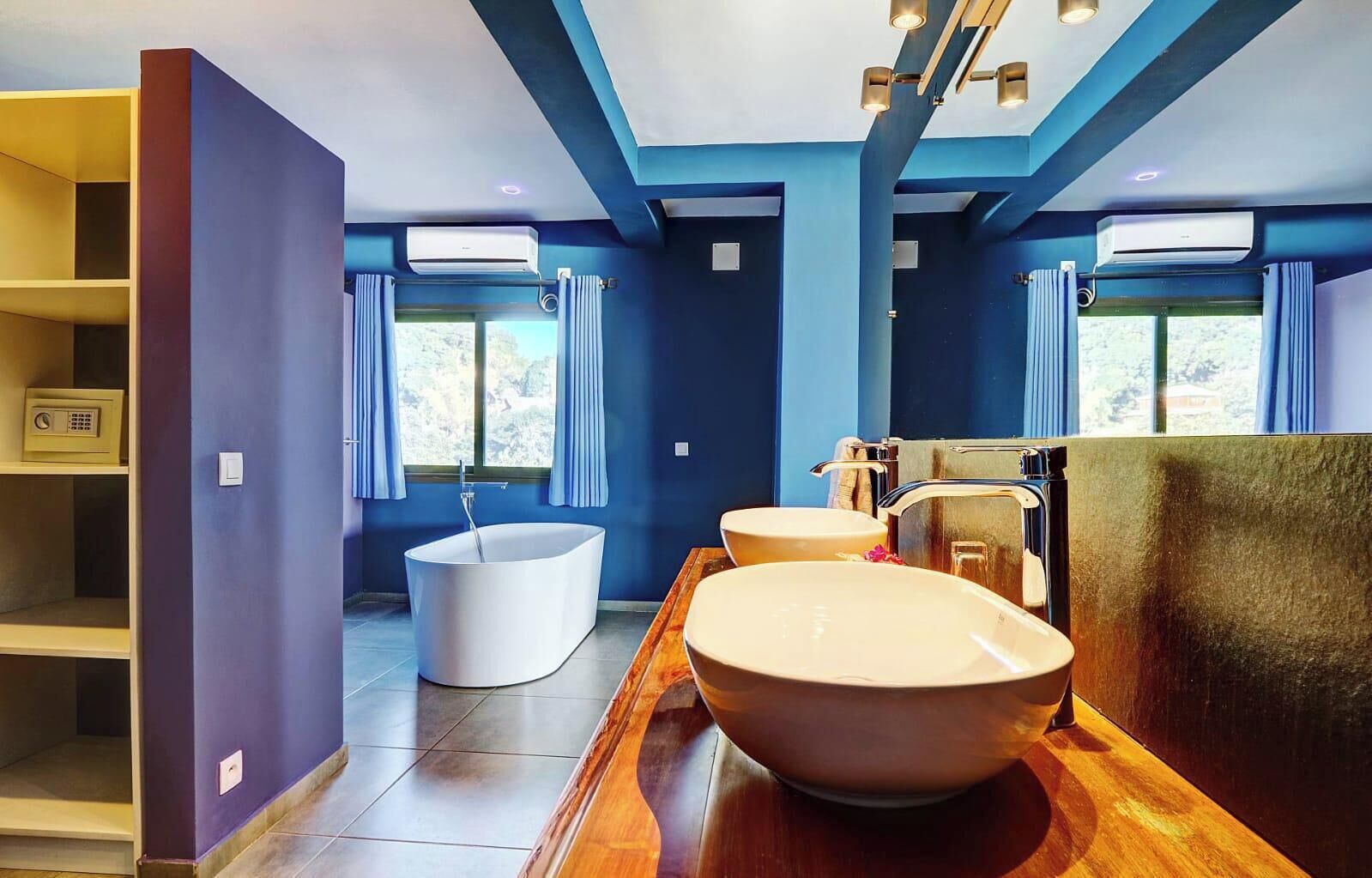 Un baño moderno con una bañera independiente, dos lavamanos y un tocador con espejo.