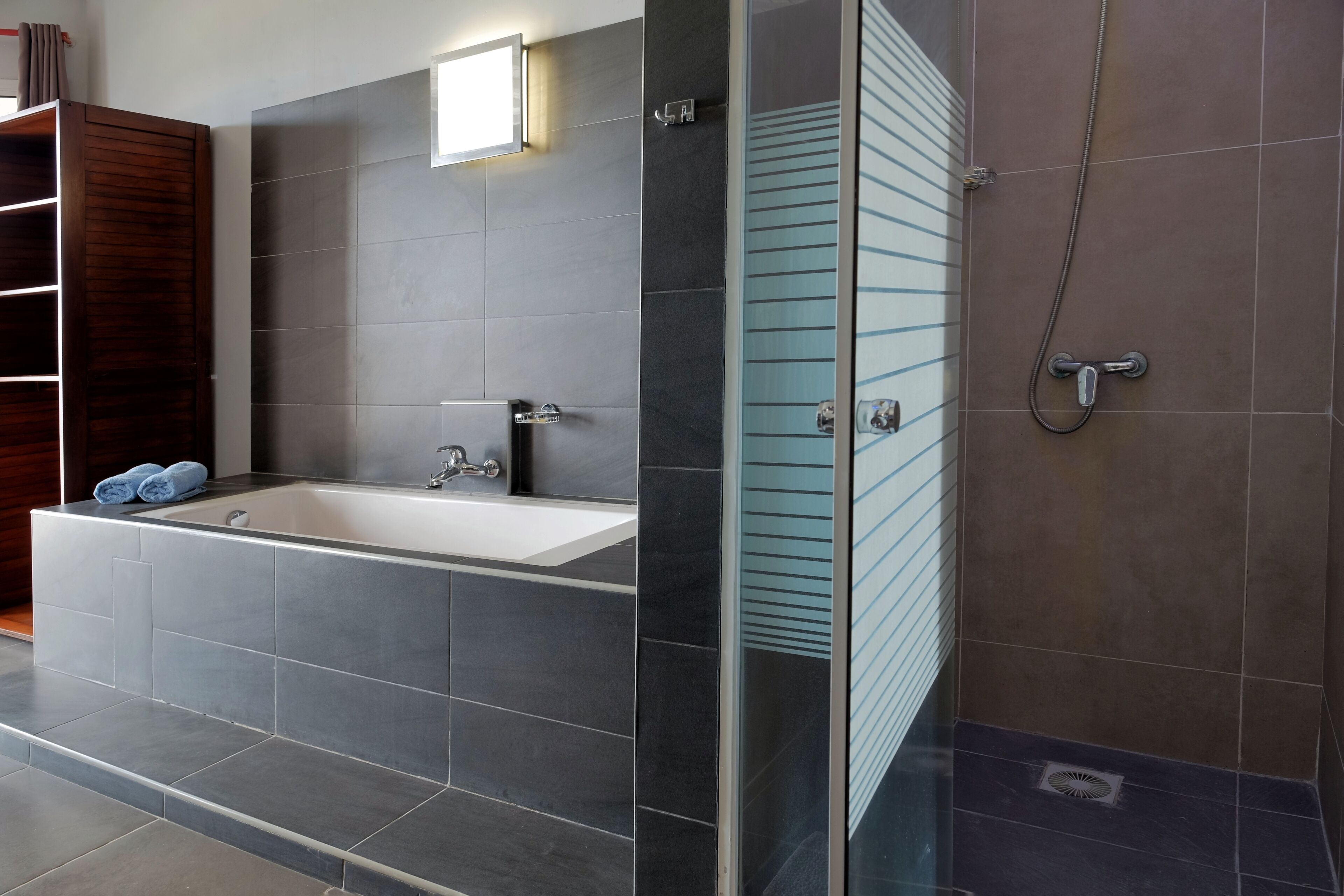 A modern bathroom with a large bathtub, a glass shower enclosure, and a wooden vanity.