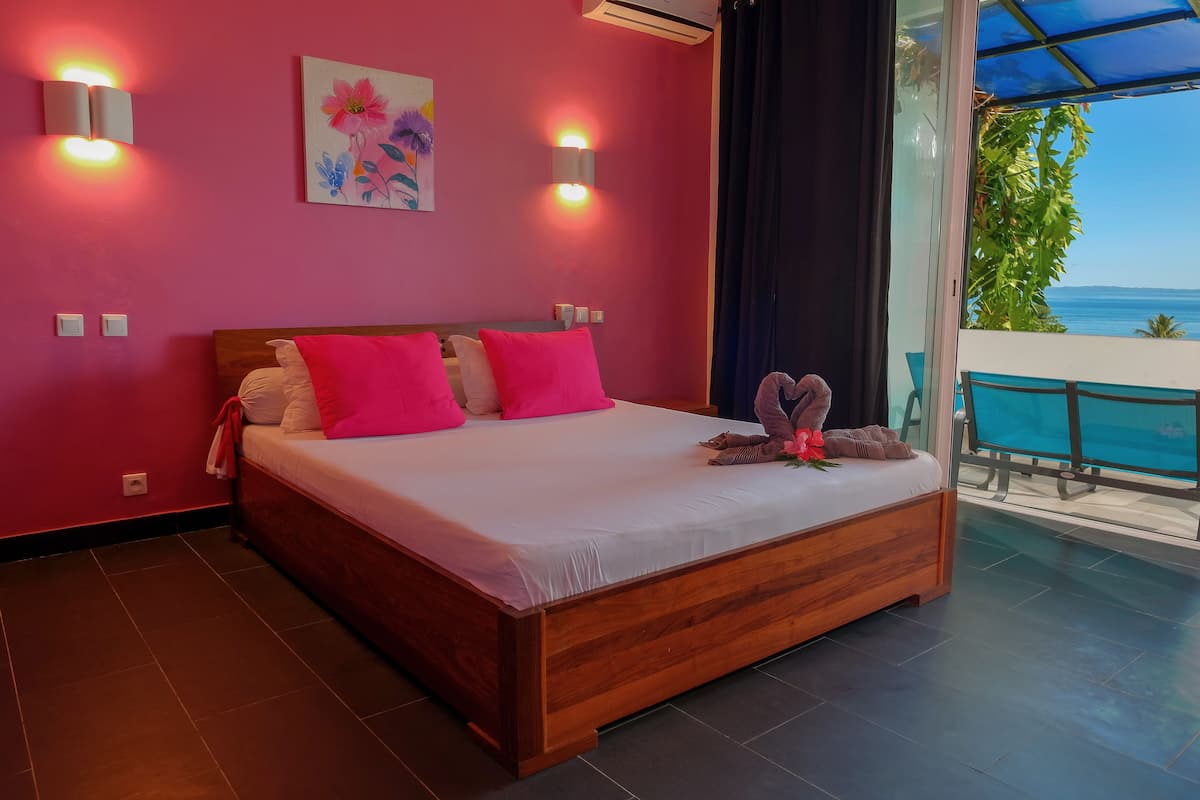Un dormitorio con una cama de madera, almohadas rosas y un cuadro floral en la pared.