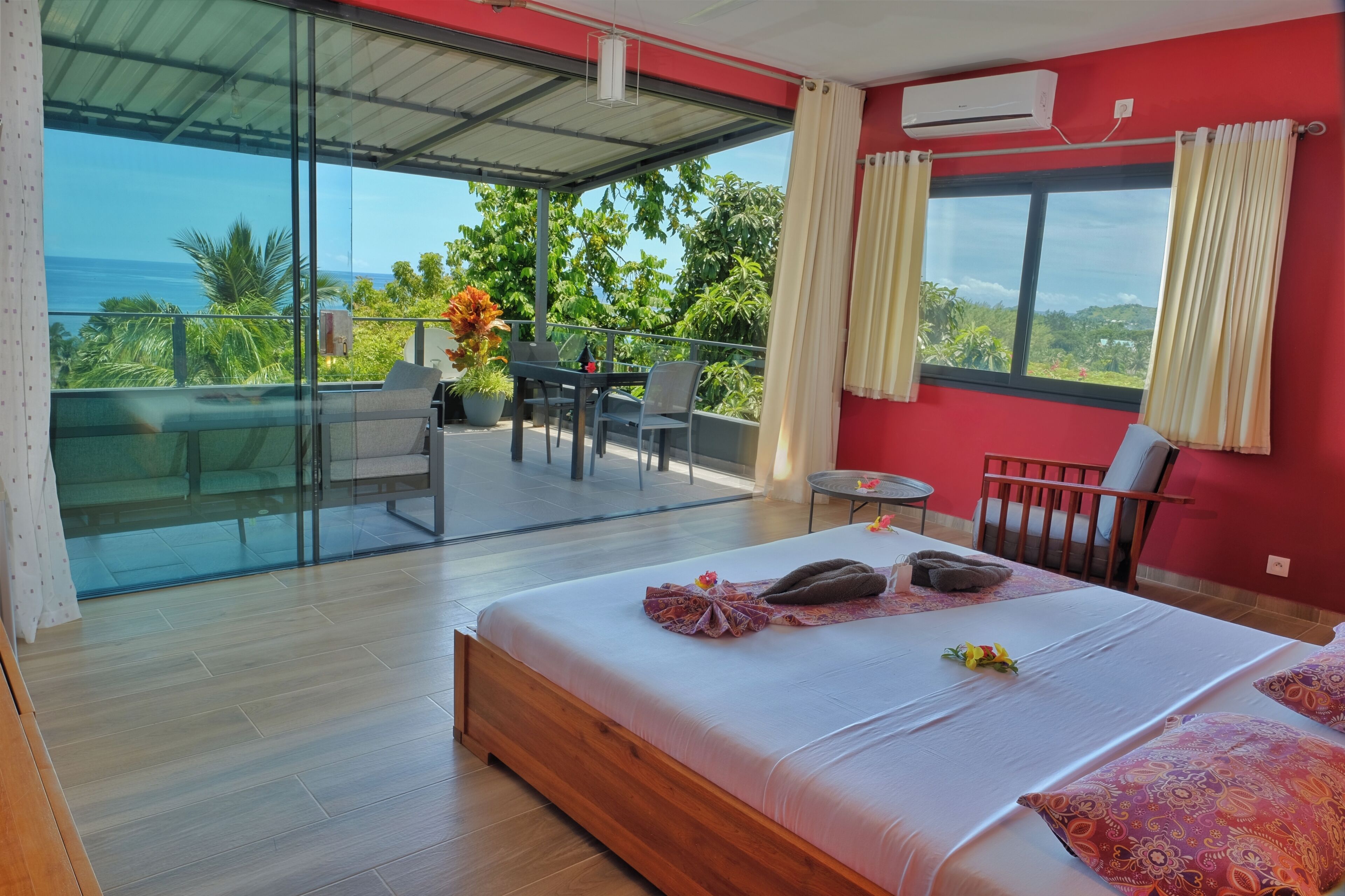Une chambre d’hôtel avec un grand lit, un balcon avec une table et des chaises, et une vue sur l’océan.